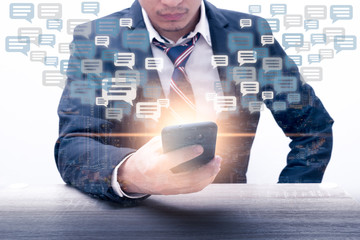 The double exposure image of the businessman using a smartphone overlay with cityscape image and message box icon. The concept of communication, business, social media and internet of things.