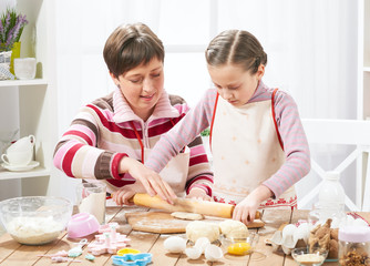 Mother and daughter cooking at home, making the dough for buns