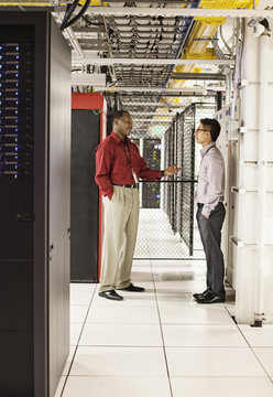 Computer technicians discussion an issue in a large computer server farm.
