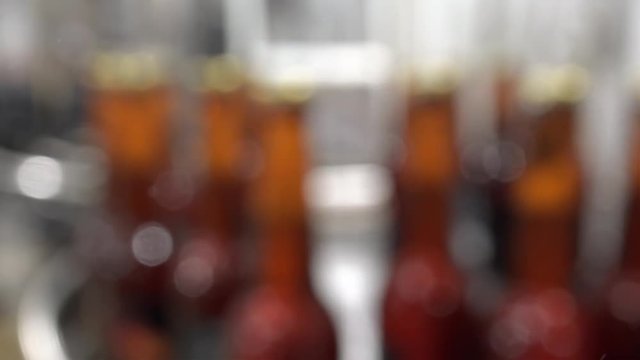 Automatic Beer Bottling Line. Queue of ready filled bottles on the conveyor. Out of focus