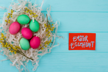 Painted Easter eggs in nest, top view. Spring time nest with red and green dyed Easter eggs decorated with branches of pussy-willow. Easter egg hunt tradition.