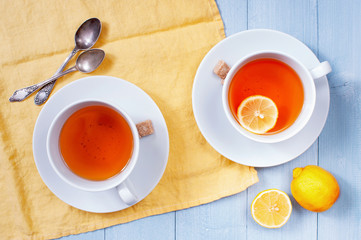 Two cups of tea with lemon on the light-blue wooden table
