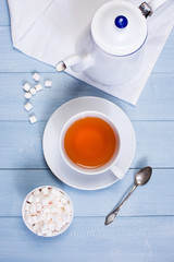 The cup of tea and white kettle on the wooden table