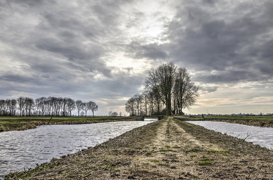 Dramatic skies above a muddy footpath with a canal on both sides near the city of Oudewater, the Netherlands