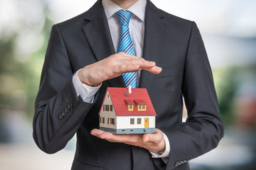 Home insurance concept. Man is holding model of house.