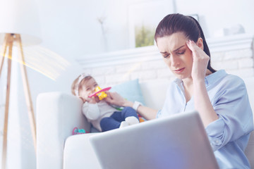 I cant stand it. Unhappy cheerless young woman holding her head and closing eyes while suffering from the headache