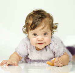Fototapeta premium The little girl is eating a bagel. The concept of a healthy baby food. white background
