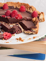 Plate with chocolate cake and raspberries on top of some books.