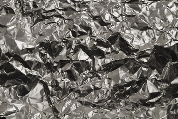 Texture of crumpled silvery gray metal foil with dents close-up