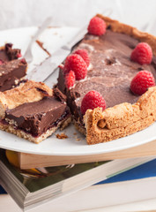 Plate with chocolate cake and raspberries on top of some books.