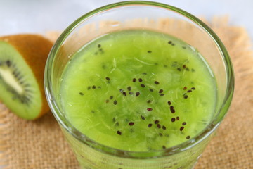 Sliced kiwi and smoothie slices in a glass on a gray table. Healthy food.