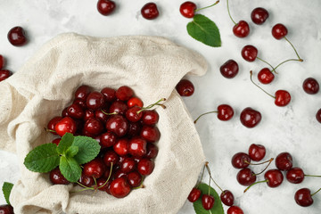 Ripe cherries and green mint leaves on a fabric.
