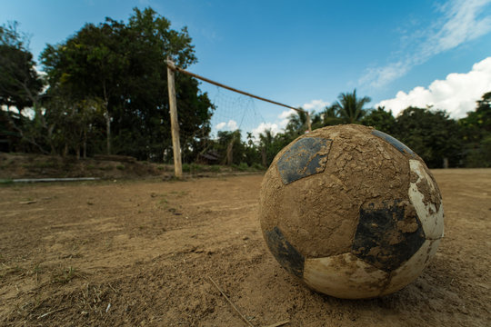 close up old football on ground at a dirt pitch