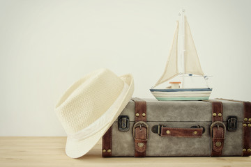 Fototapeta na wymiar traveler vintage luggage, boat and fedora hat over wooden table. holiday and vacation concept.
