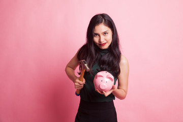 Asian woman with pig coin bank and hammer.