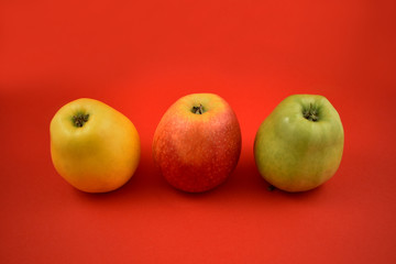 Three colorful apples stock images. Apples on a red background. Three ripe apples. Red, green, yellow apple isolated on a colorful background