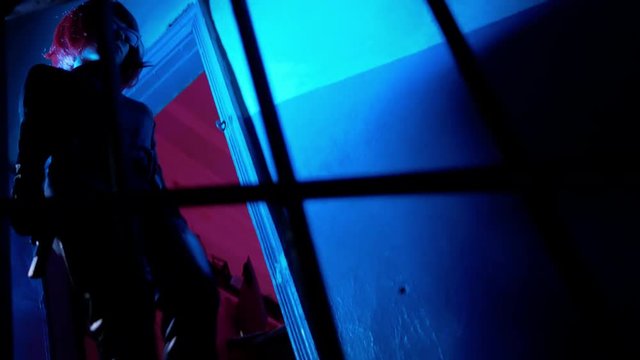 Danger killer woman with red hair walks down at stairs with gun at dark place