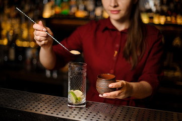 Female bartender putting a cane sugar into a glass