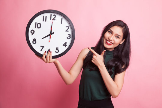 Young Asian woman point to a clock.