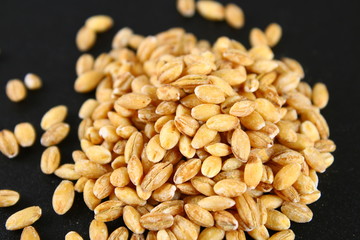 Dry pearl barley with a handful on a black chalkboard.