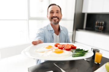 Delightened mature man passing a plate