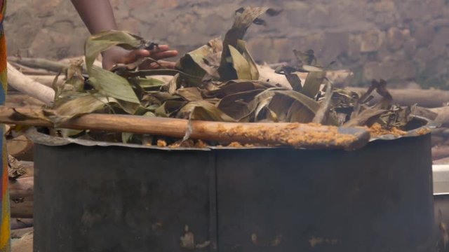 Putting palm tree leaves on a steaming pot