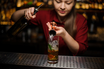Female bartender filling a liqour from the measuring pile