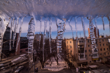 A number of melting icicles on the background of a city street.
