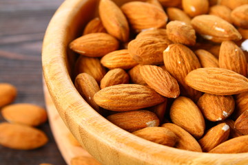 Raw dry nuts of almonds in a wooden bowl on a wooden table.