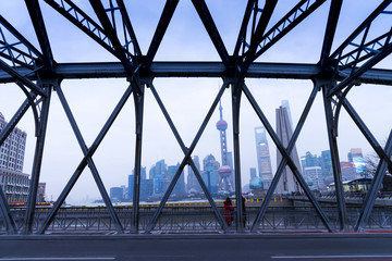 view of Shanghai cityscape with steel bridge structure, high rises office and towers of the Business district skyline at mist behind a pollution haze, across Huangpu river, Shanghai, China.
