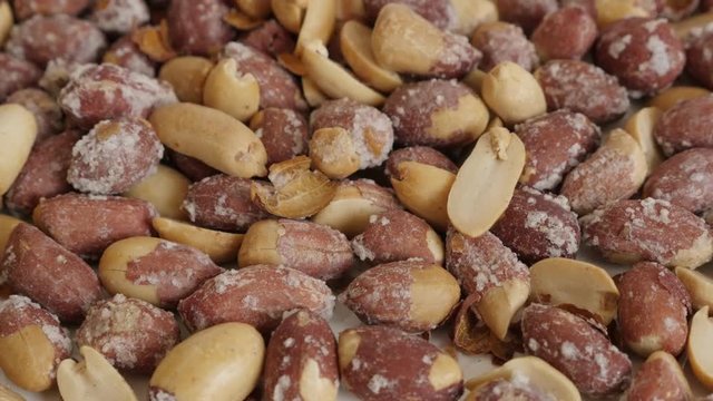 Tilting over salted groundnuts on pile close-up footage - Roasted Arachis hypogaea snack slow tilt