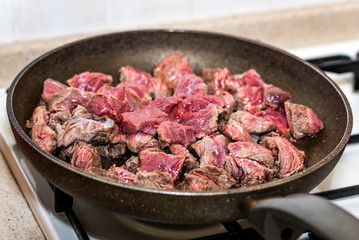 Pieces of beef cooking in frying pan
