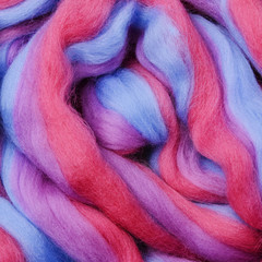 Bright colored merino wool for felting and needlework, hobby. The stripes of pink, blue and violet color yarn folded into abstract pattern. Abstract art background