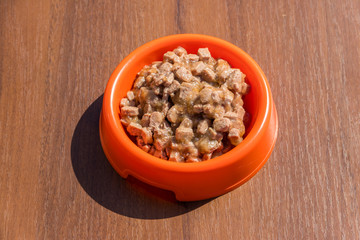 Canned food for cats or dogs in a orange plastic bowl