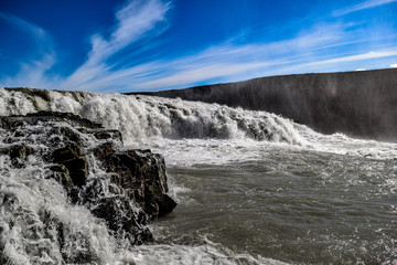 Raging waterfall in Iceland over volcanic rocks off of the glaciers