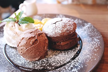 A Chocolate muffin served with chocolate ice cream, whipped cream and banana, that's topped with caramel syrup. on wooden background