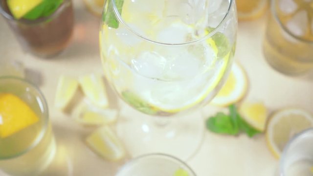 The camera moves to a glass of liquid pours into a glass with mint and ice slow motion