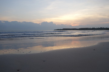 Fototapeta premium Empty beach at early morning, pink sunrise reflected in water