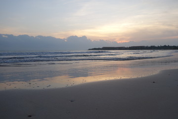 Empty beach at early morning, pink sunrise reflected in water