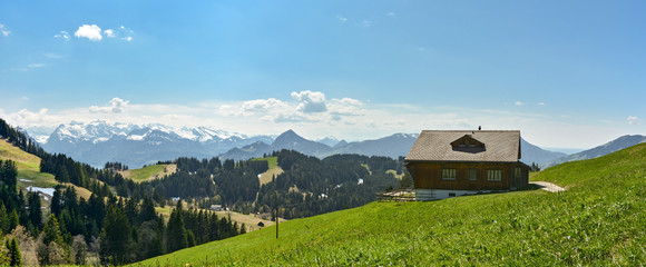 Beautiful swiss scenery with mountain hut and snowy Alps in the background