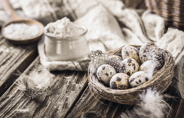 Quail eggs in a nest and flour on a rustic wooden background.