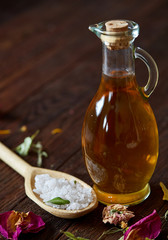 SPA concept: composition of spa treatment with natural sea salt, aromatic oil and flowers on wooden background