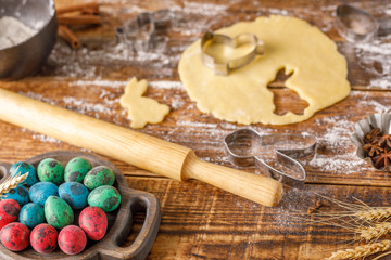 Dough for cooking curly cookies for Easter and painted quail eggs on a wooden background.