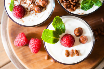 Dessert with berries, jelly, cream, nuts and mint leaf on a cutting wooden board