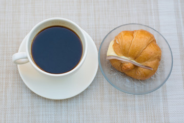 A cup of Black coffee with Ham and cheese croissant