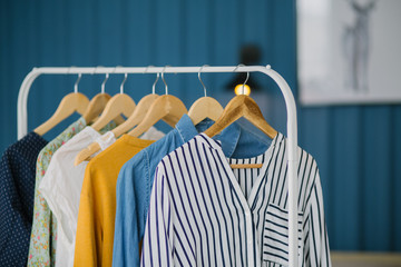 Clothes hang on wooden coat hangers in clothing store with home tone. Shopping and spending concept