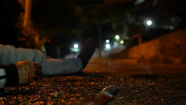 A VIOLENCE VICTIM ON THE GROUND AT NIGHT AND A KNIFE IS THROWN