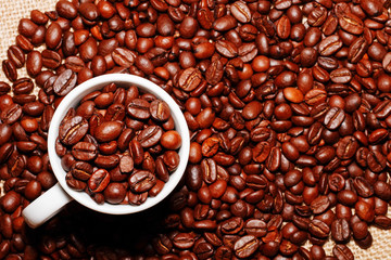 White cup and coffee beans on the background of sacking. view from above