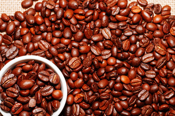 White cup and coffee beans on the background of sacking. view from above