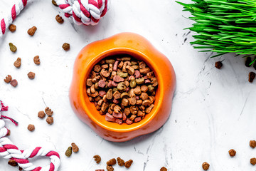 dry cat food in bowl on stone background top view